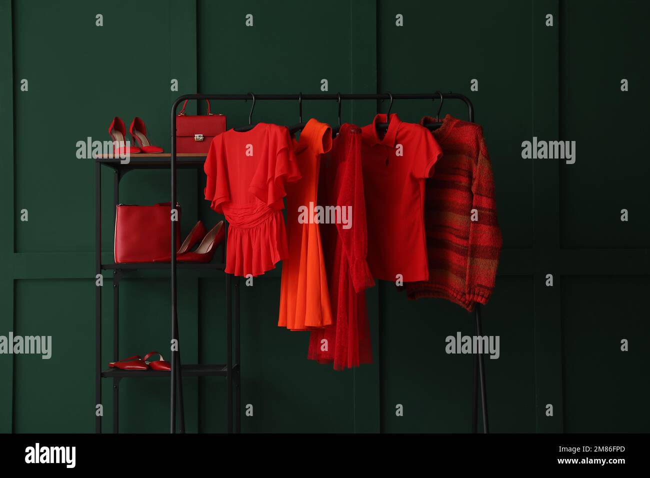 Rack with red female clothes, shelving unit and shoes near green wall ...