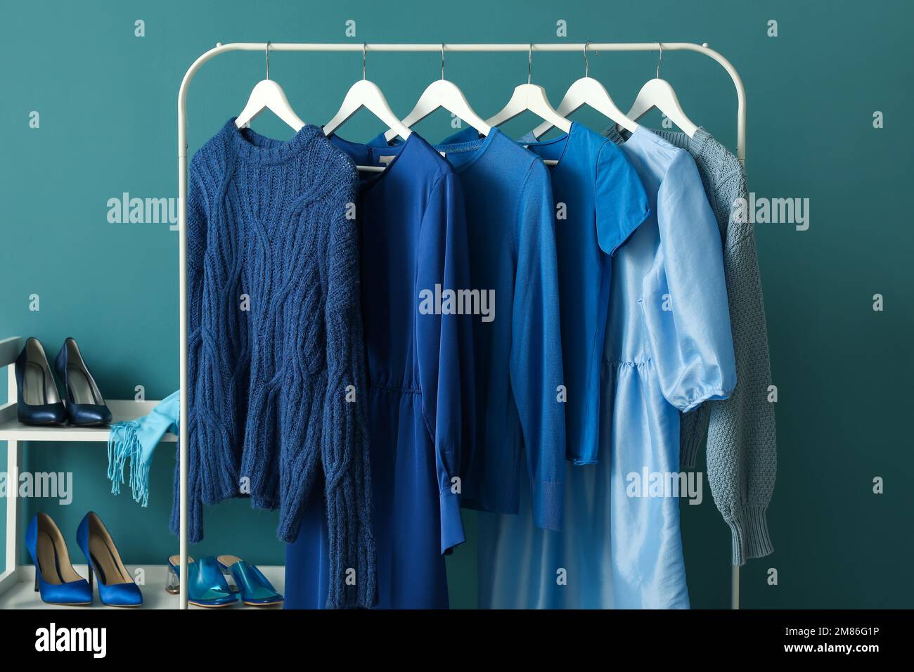 Rack with blue clothes and shoe stand near color wall Stock Photo - Alamy