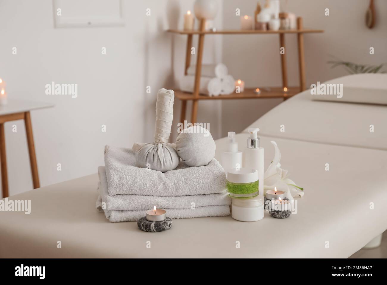 Spa composition with lily flower and burning candles on couch in salon ...
