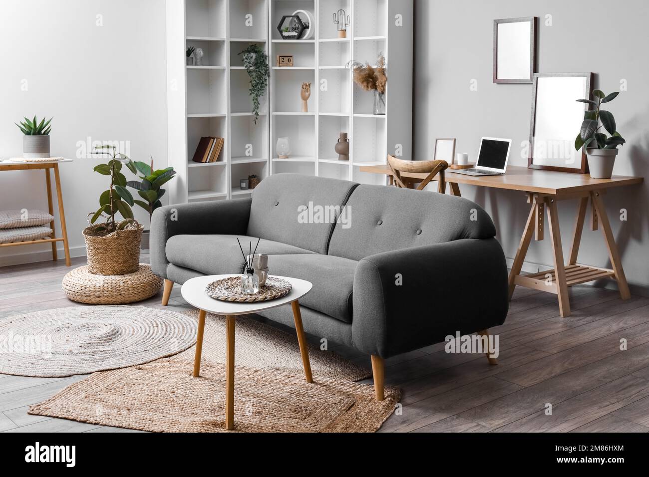 Stylish interior of living room with grey sofa, table and wicker pouf ...