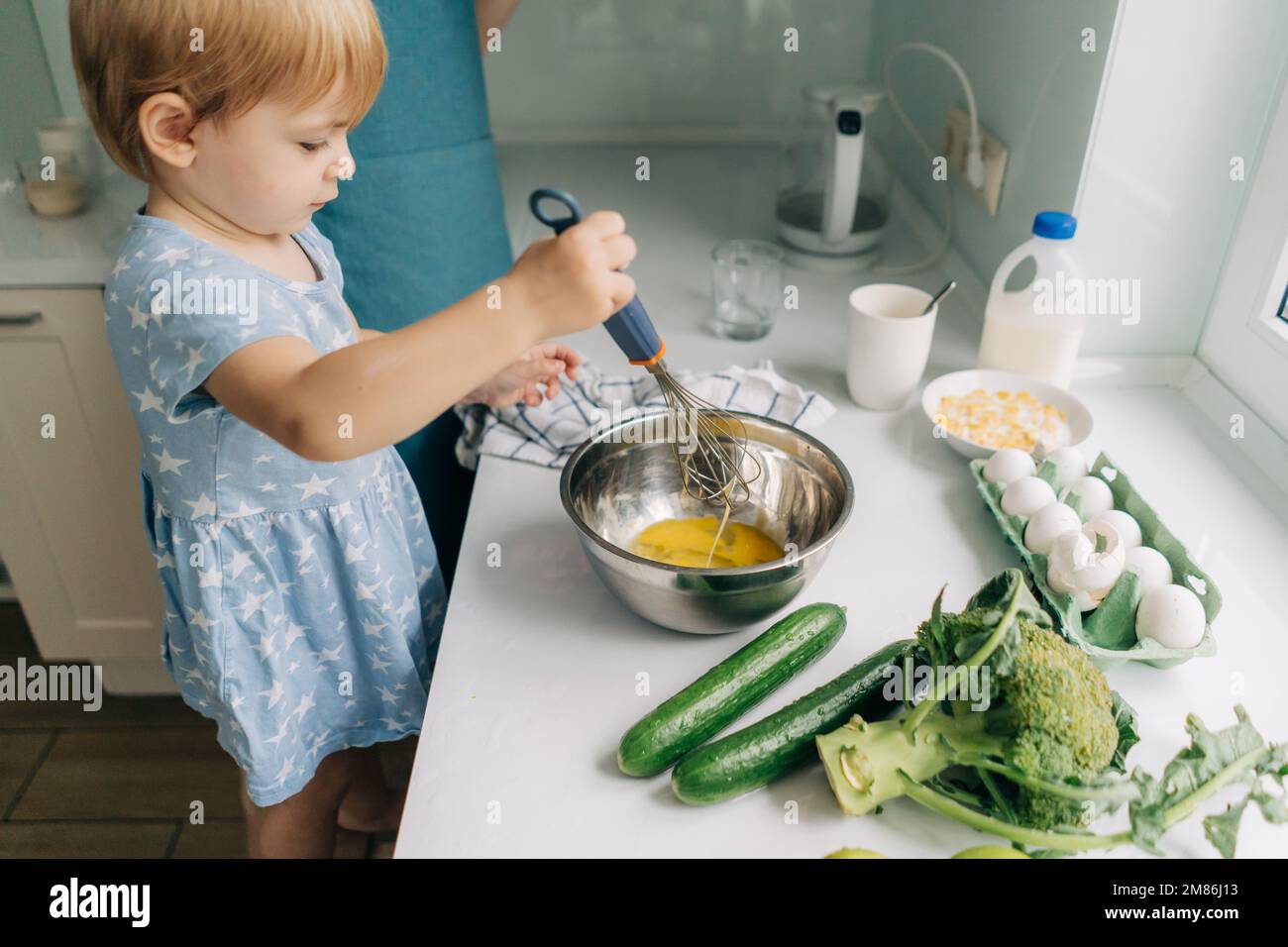 Toddler little daughter helps mom cook dinner Stock Photo Alamy