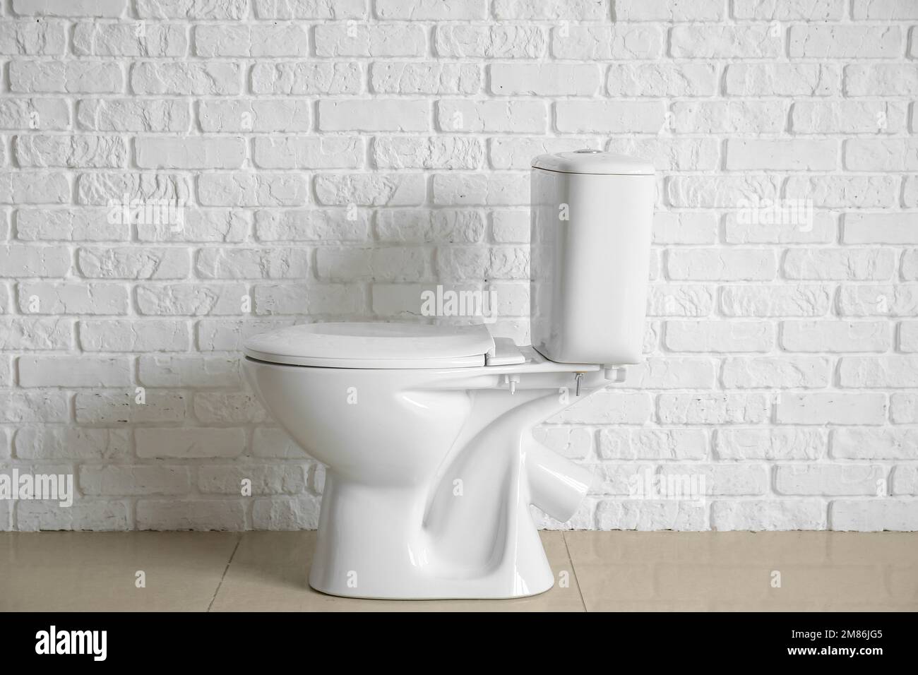 Modern toilet bowl near white brick wall Stock Photo Alamy