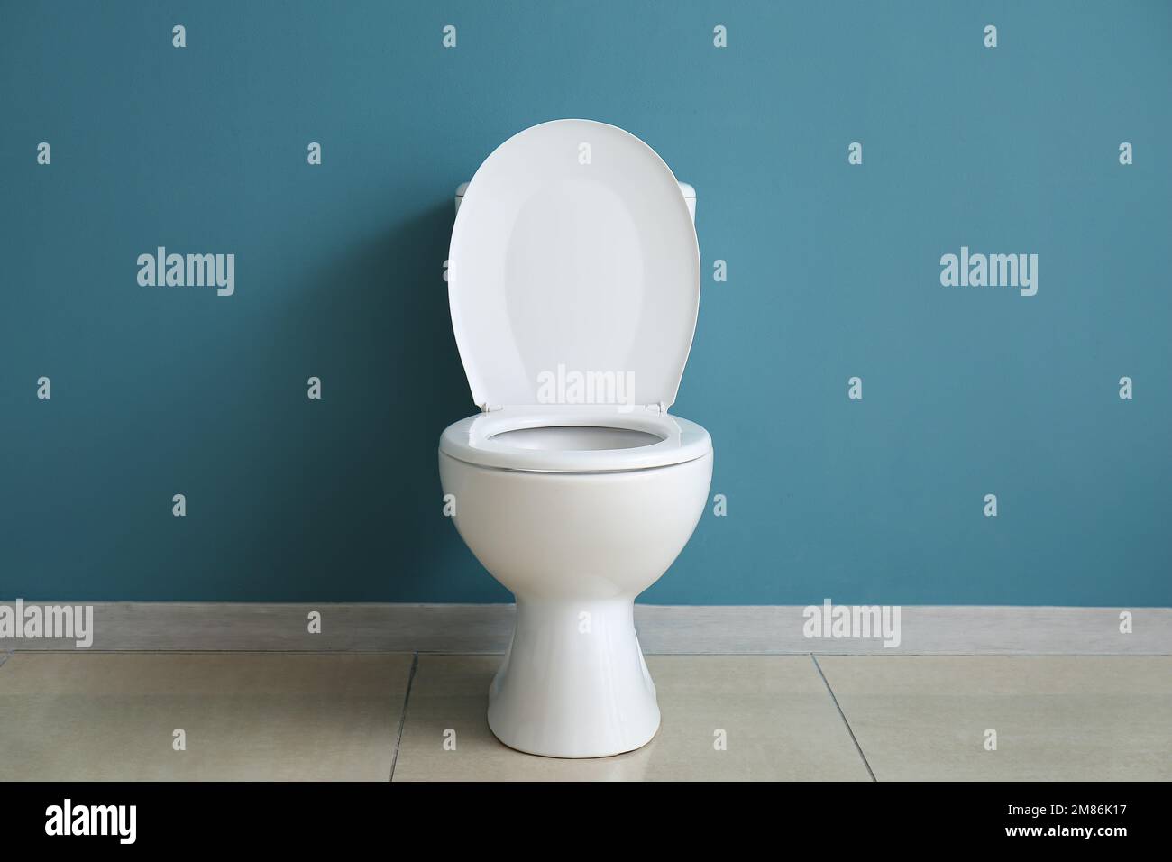 Ceramic toilet bowl near blue wall Stock Photo Alamy