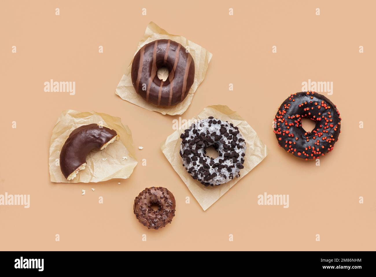 Parchments with different delicious donuts on beige background Stock Photo