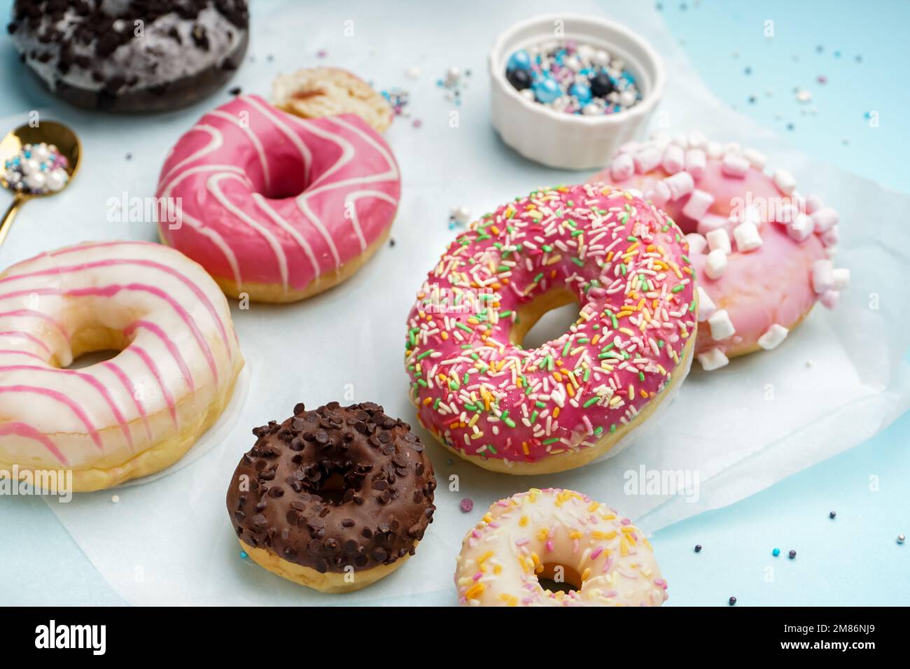 Parchment with different delicious donuts on blue background Stock Photo