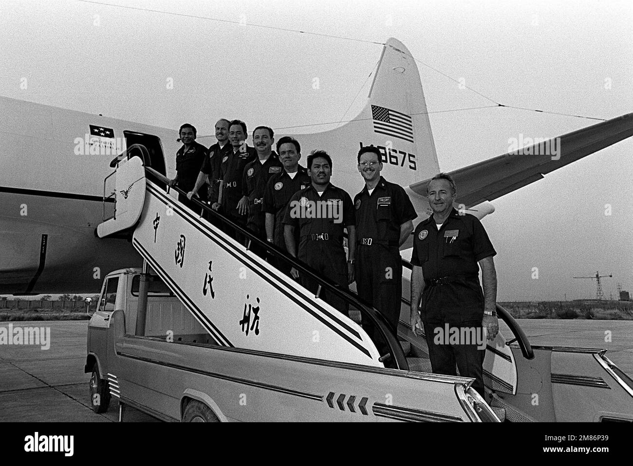 Crewmen of the first Orion aircraft to land in China pose for a photograph after arriving at Qingdao Airport. They are, from the bottom of the ramp, LCDR Jerry Jackson, aircraft commander; ATC Michael D. West, MS1 Tony Aquino, ADCS Ronald Montgomery, SCPO Michael Bobbit, RMC Armando M. Carillo, LCDR Wayne Jones and MSC Angel Galas. The VP-3A Orion aircraft is used by ADM James A. Lyons Jr., commander in chief, US Pacific Fleet, and will transport Lyons and his staff back to Hawaii after a port visit by U.S. Navy ships. Base: Qingdao State: Shanghi Country: China (CHN) Stock Photo
