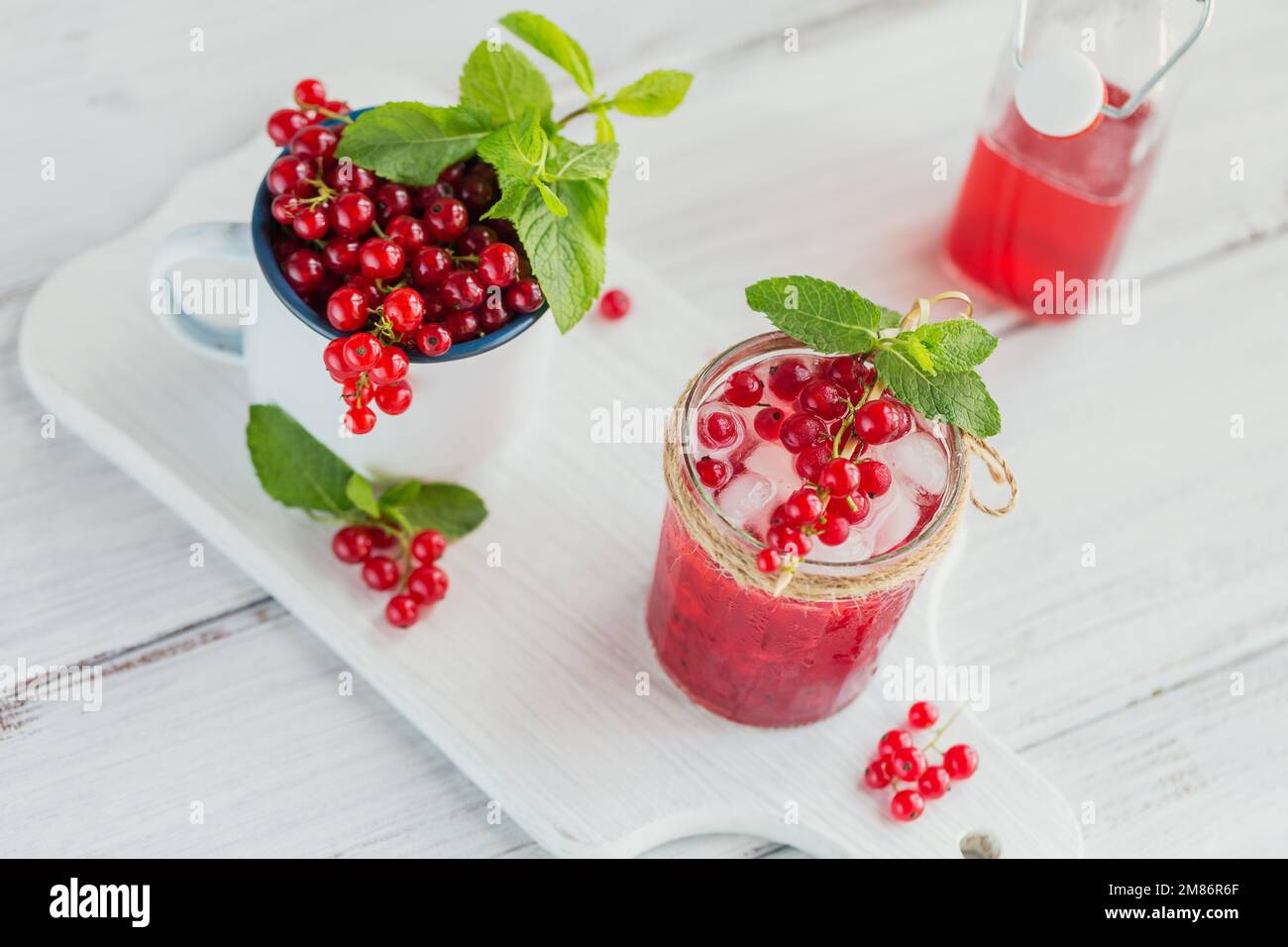 Summer drink with white sparkling wine. Homemade refreshing fruit cocktail or punch with champagne, red currant, ice cubes and mint leaves on white Stock Photo