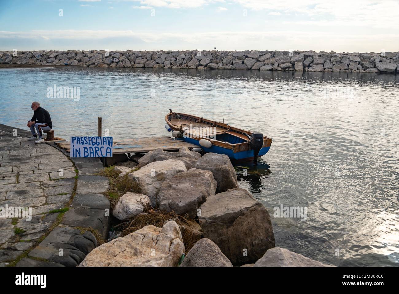 Naples, Italy - December 25, 2022: Winter day on the Mediterranean coast. A man rents a boat at the seafront in Naples, Campania, Italy. Stock Photo