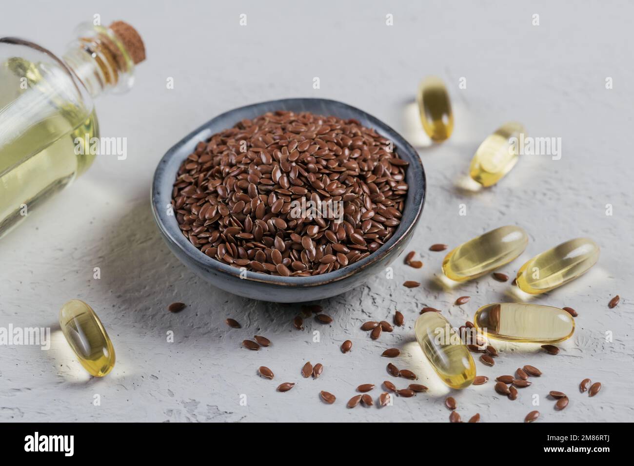 Brown flax seed or linseed in small bowl and gelatin capsules with