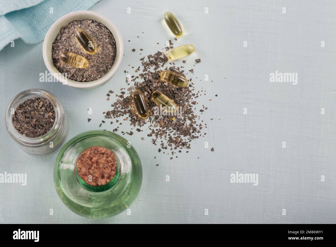 Gelatin capsules with algae omega oil and seaweed on a light blue