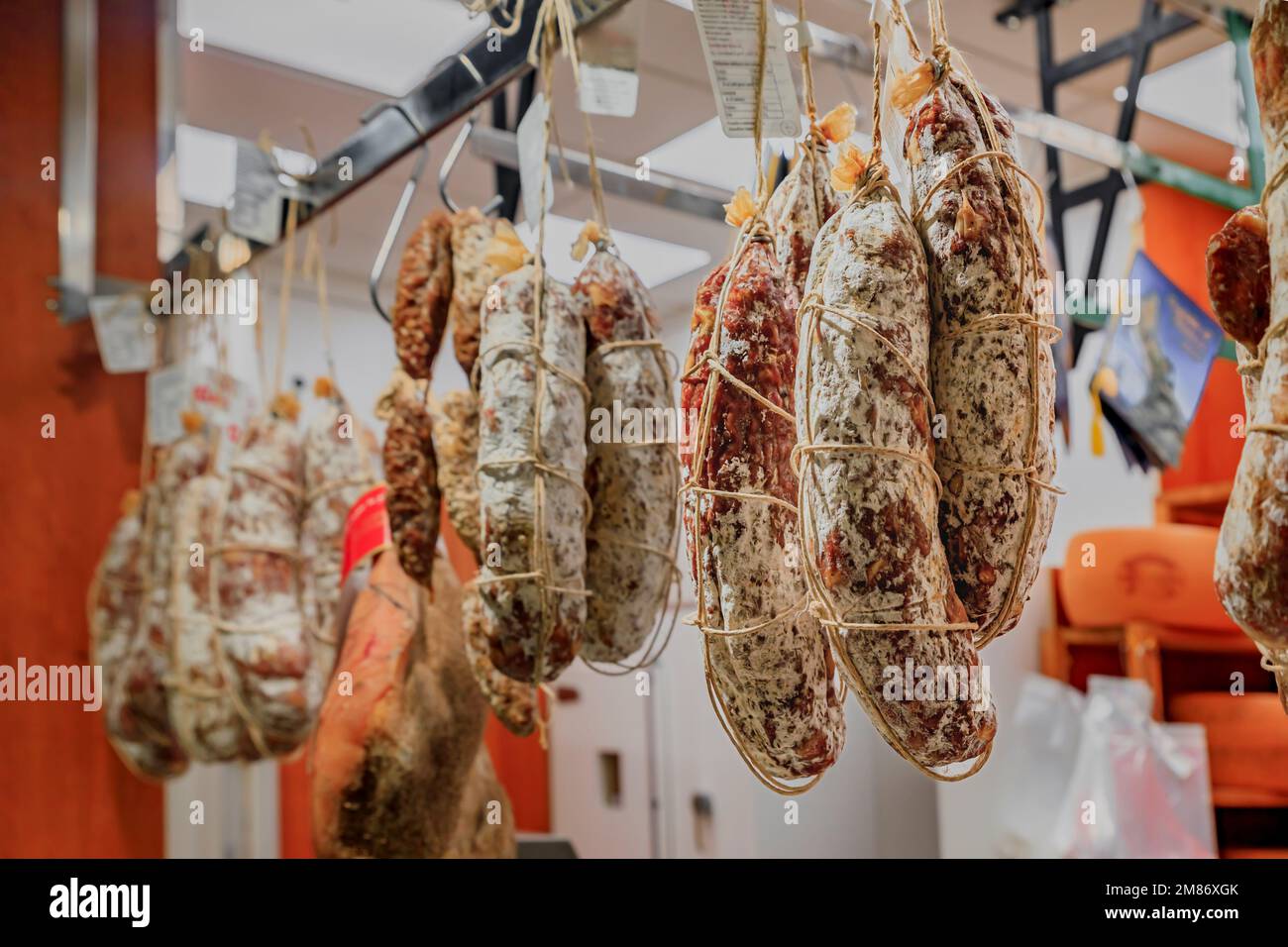 Salami sausage on display for sale hanging at a salumeria meat and cheese shop in Central Market Mercato Centrale in Florence, Italy Stock Photo