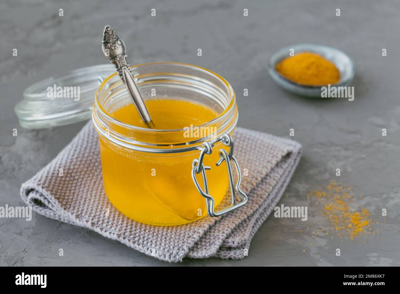 Homemade Ghee or clarified butter in a jar and turmeric powder on grey ...