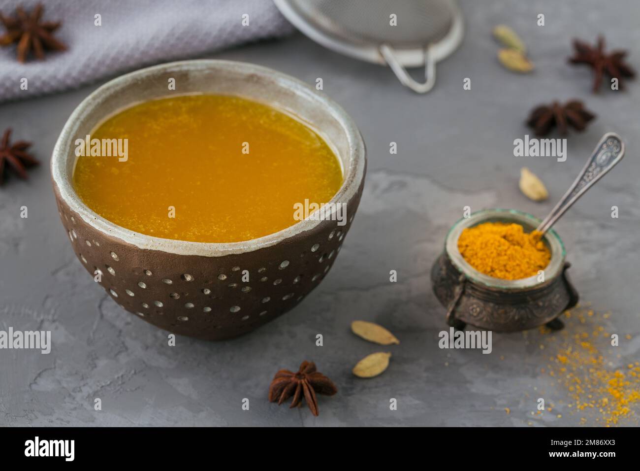 Healthy homemade Ghee or clarified butter in a jar and turmeric powder on grey concrete