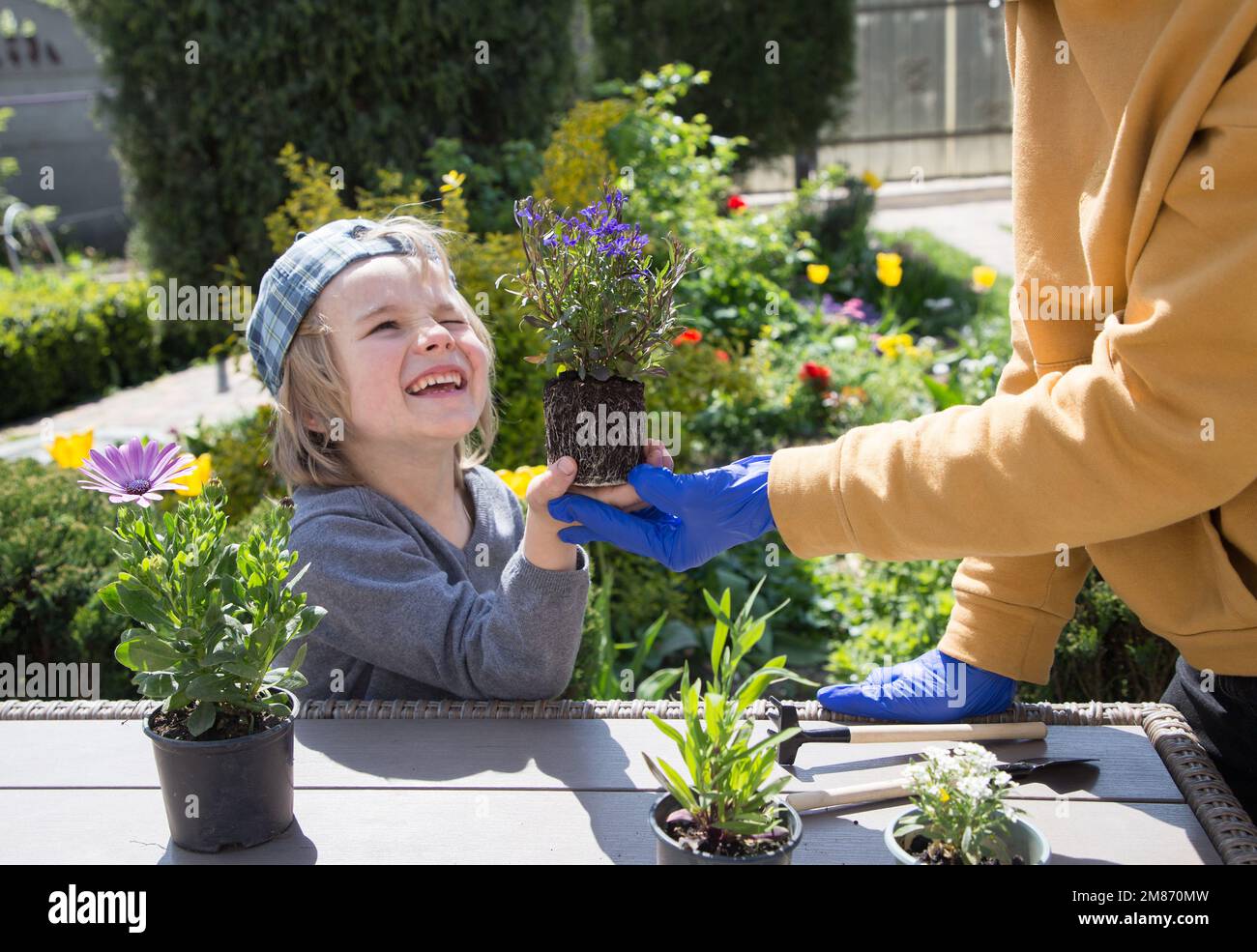 mom and little son are getting ready to plant flowers in garden