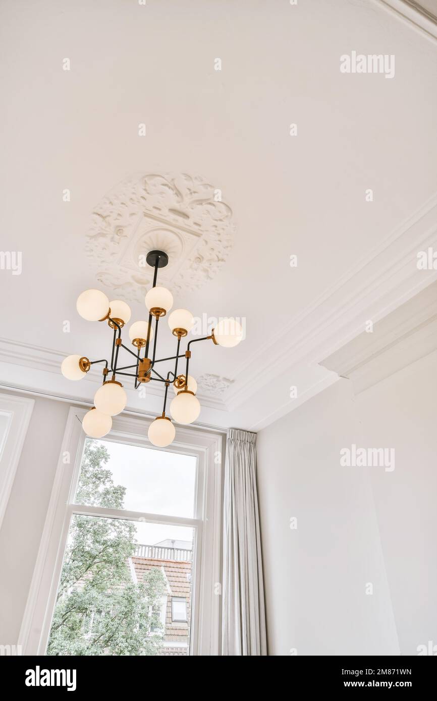 a room with white walls and light fixtures hanging from the ceiling to the floor, there is a large window Stock Photo