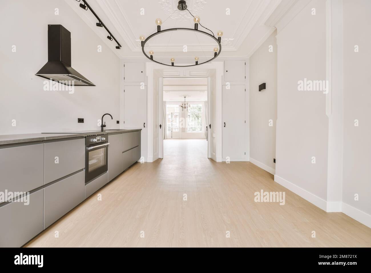 an empty kitchen with white walls and light wood flooring in the center ...