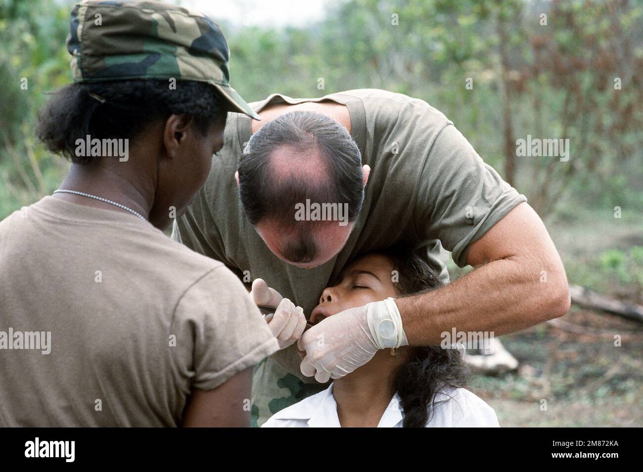 Members of a medical team give a village girl a dental exam during an