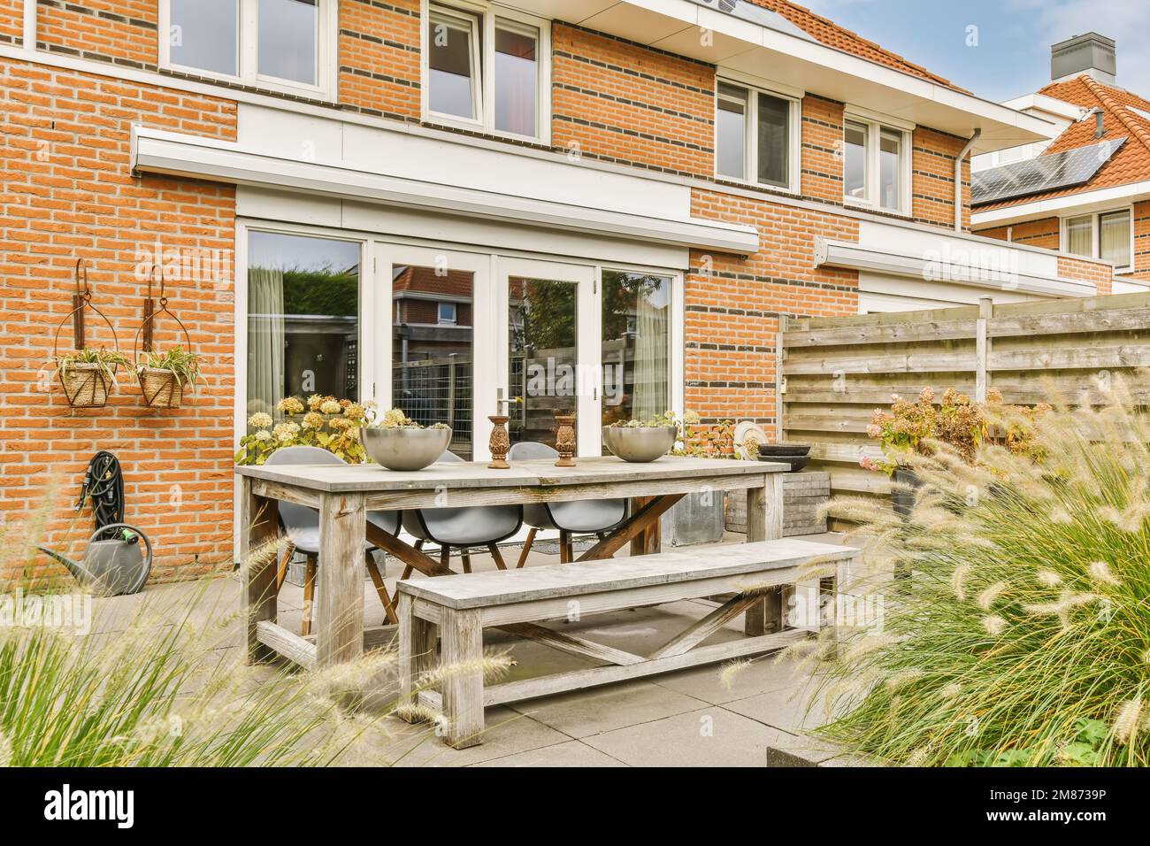 an outside area with a table, chairs and bench in front of a brick wall ...