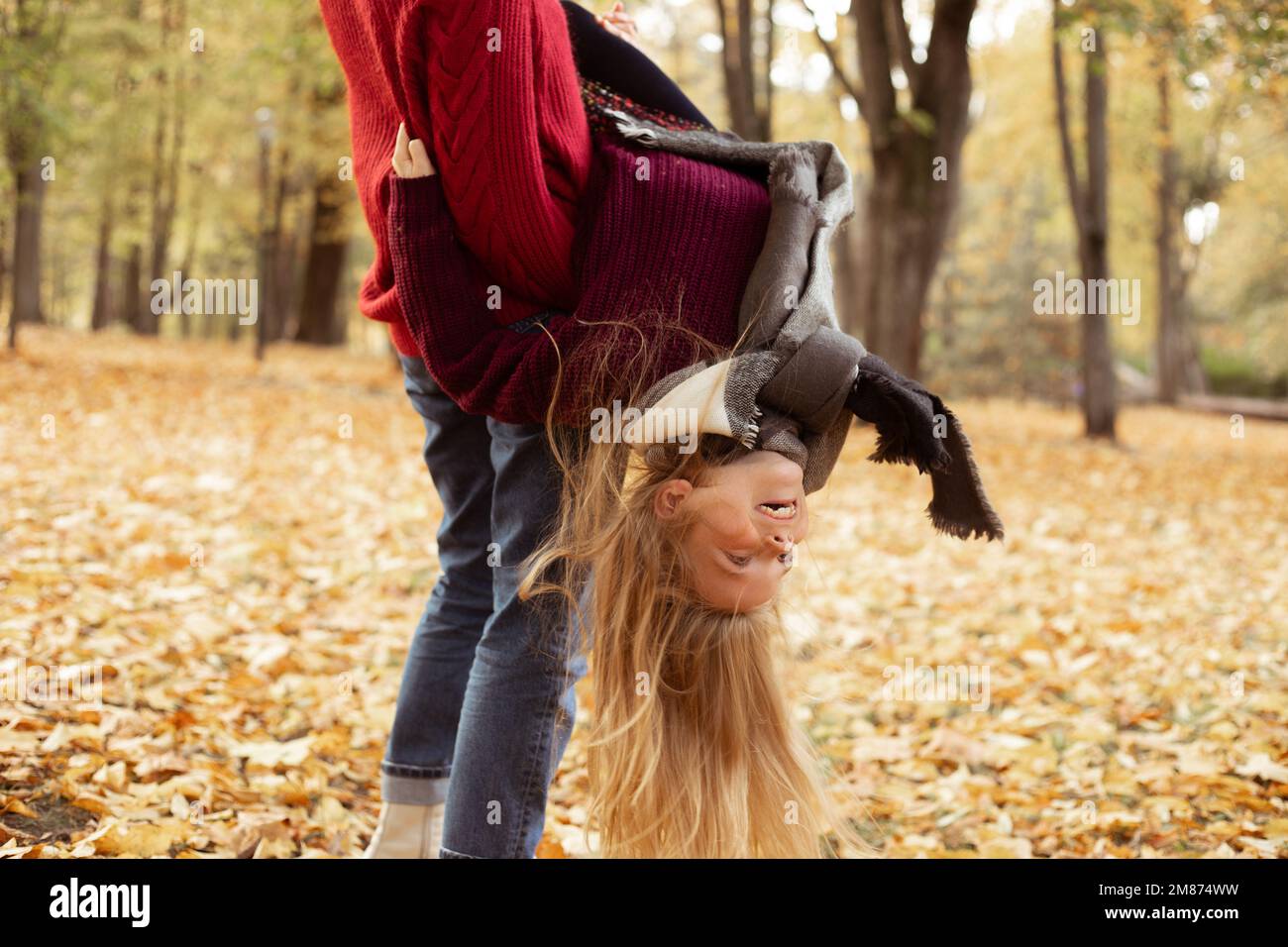 Funny, playful, cheerful, glad, mischief cropped mother and daughter play and have fun together in autumn forest. Family Stock Photo