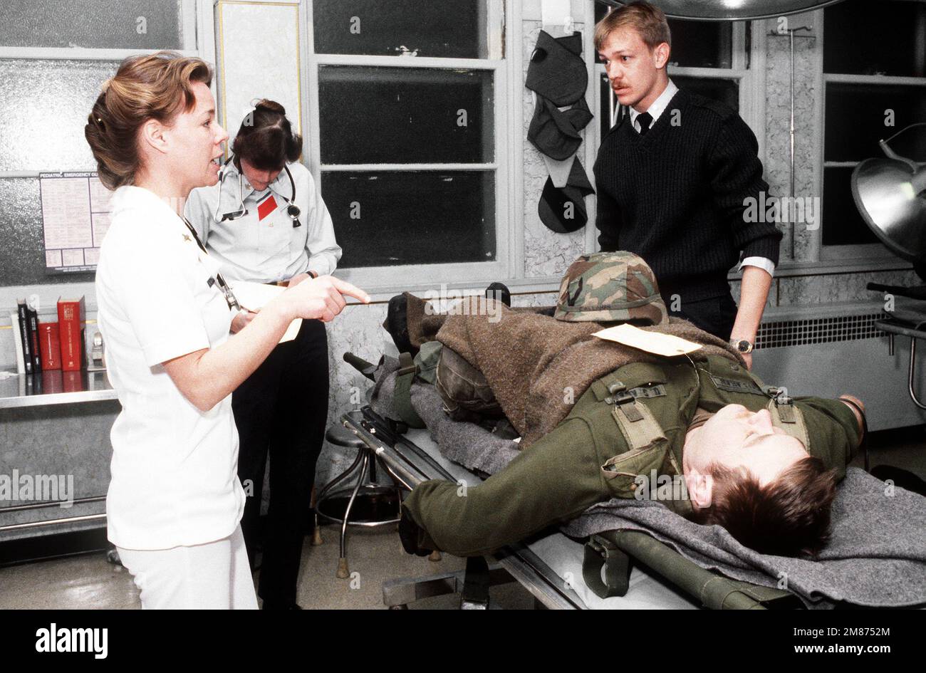A soldier with a simulated wound is treated by Coast Guard medical personnel at the Coast Guard Air Station during exercise Brim Frost '87. Subject Operation/Series: BRIM FROST '87 Base: Kodiak State: Alaska (AK) Country: United States Of America (USA) Stock Photo