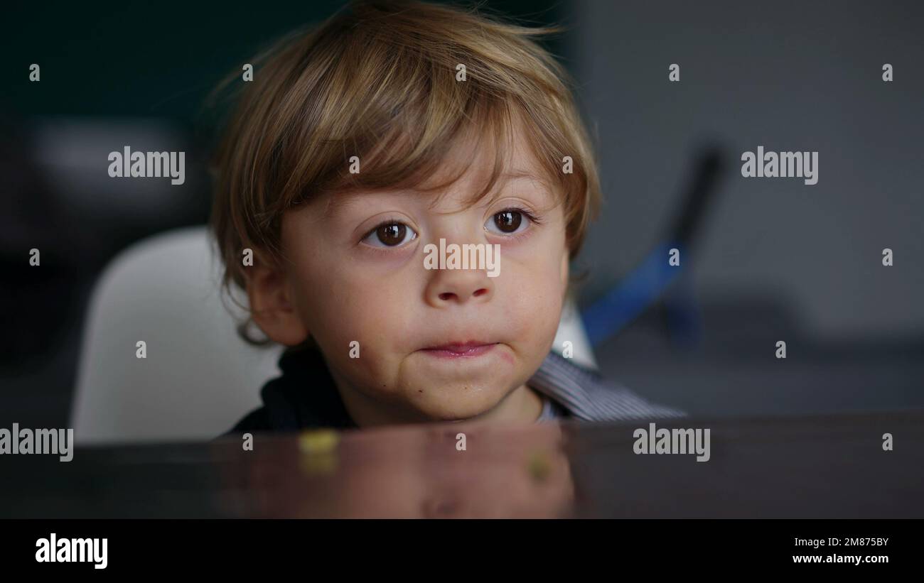 Baby toddler hypnotized by screen, kid biting table while watching