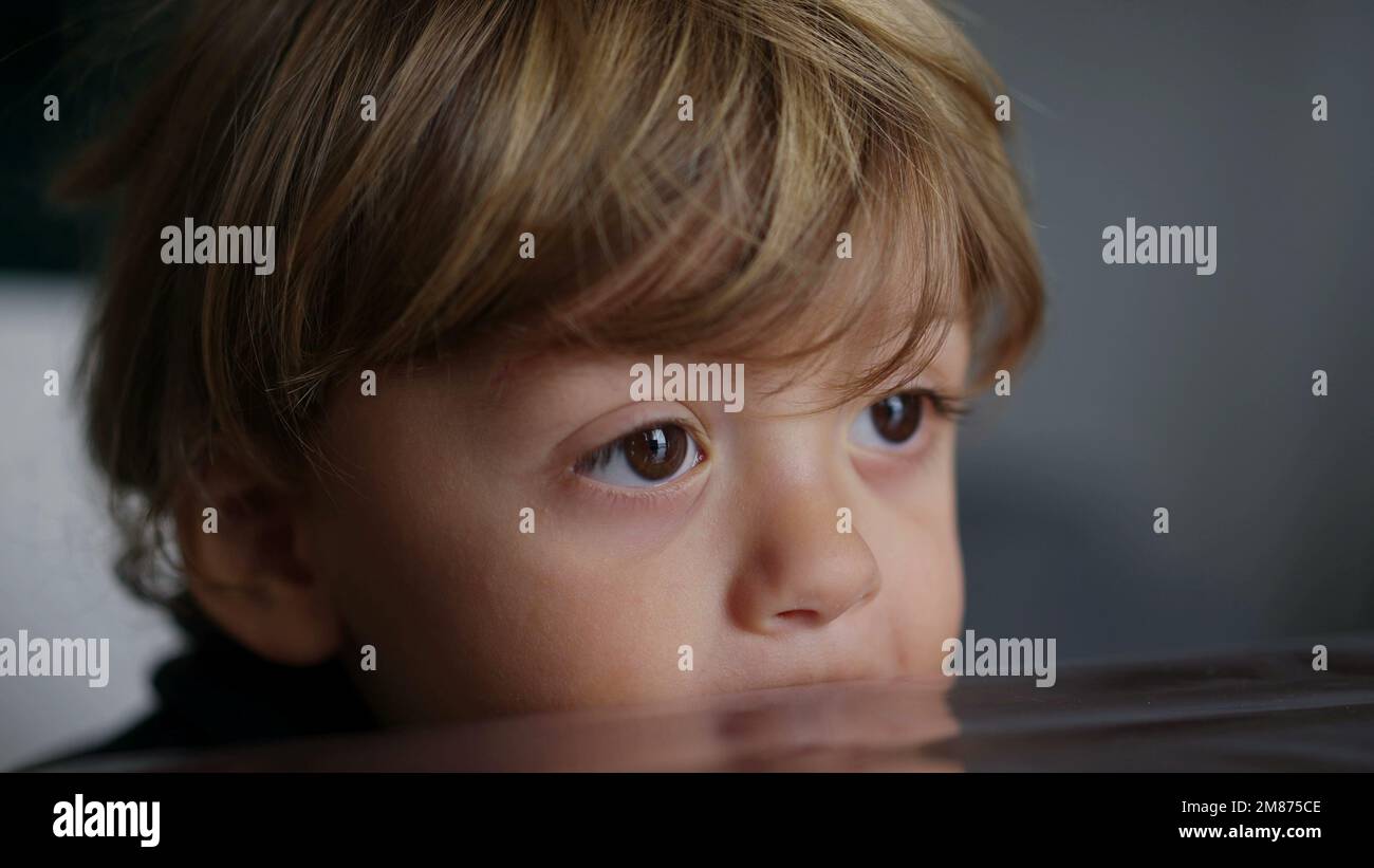 Baby toddler hypnotized by screen, kid biting table while watching