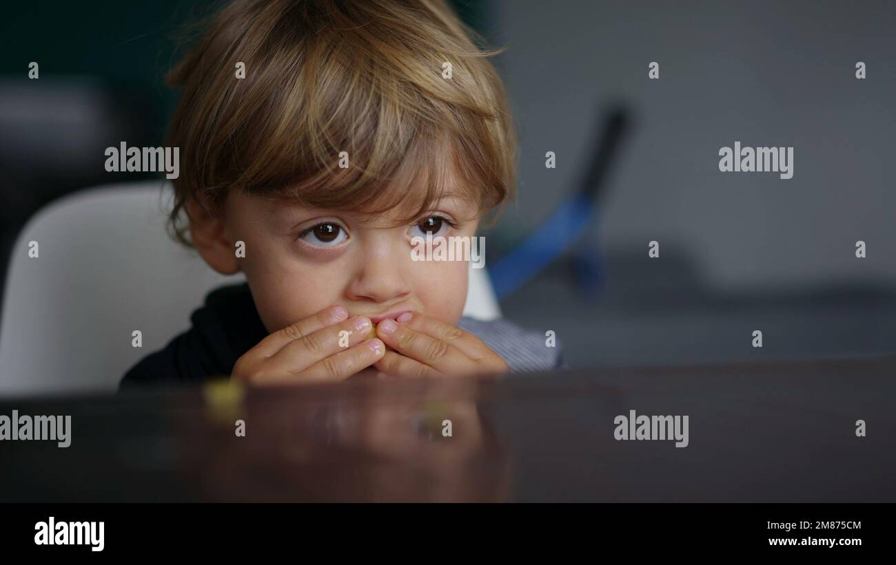 Baby toddler hypnotized by screen, kid biting table while watching