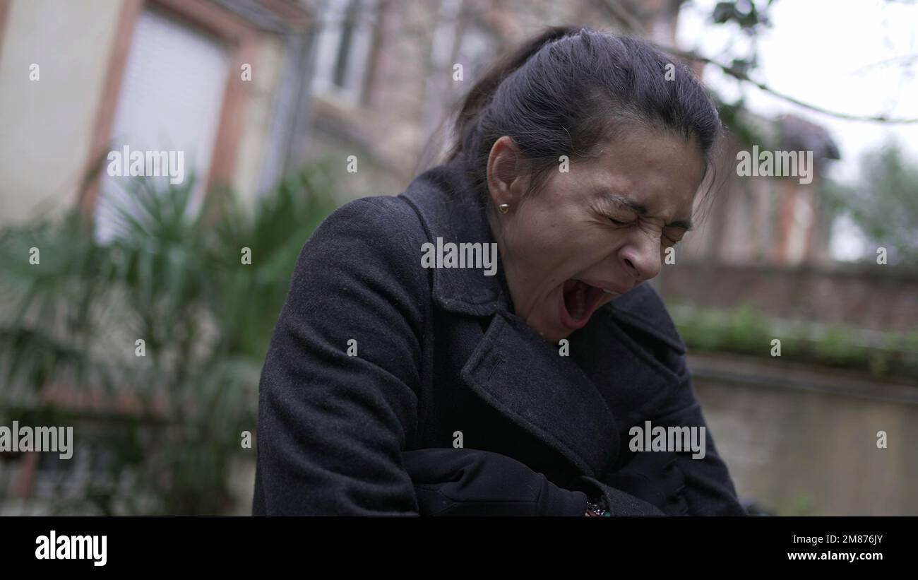 Tired exhausted woman yawning while standing outside in the cold Stock