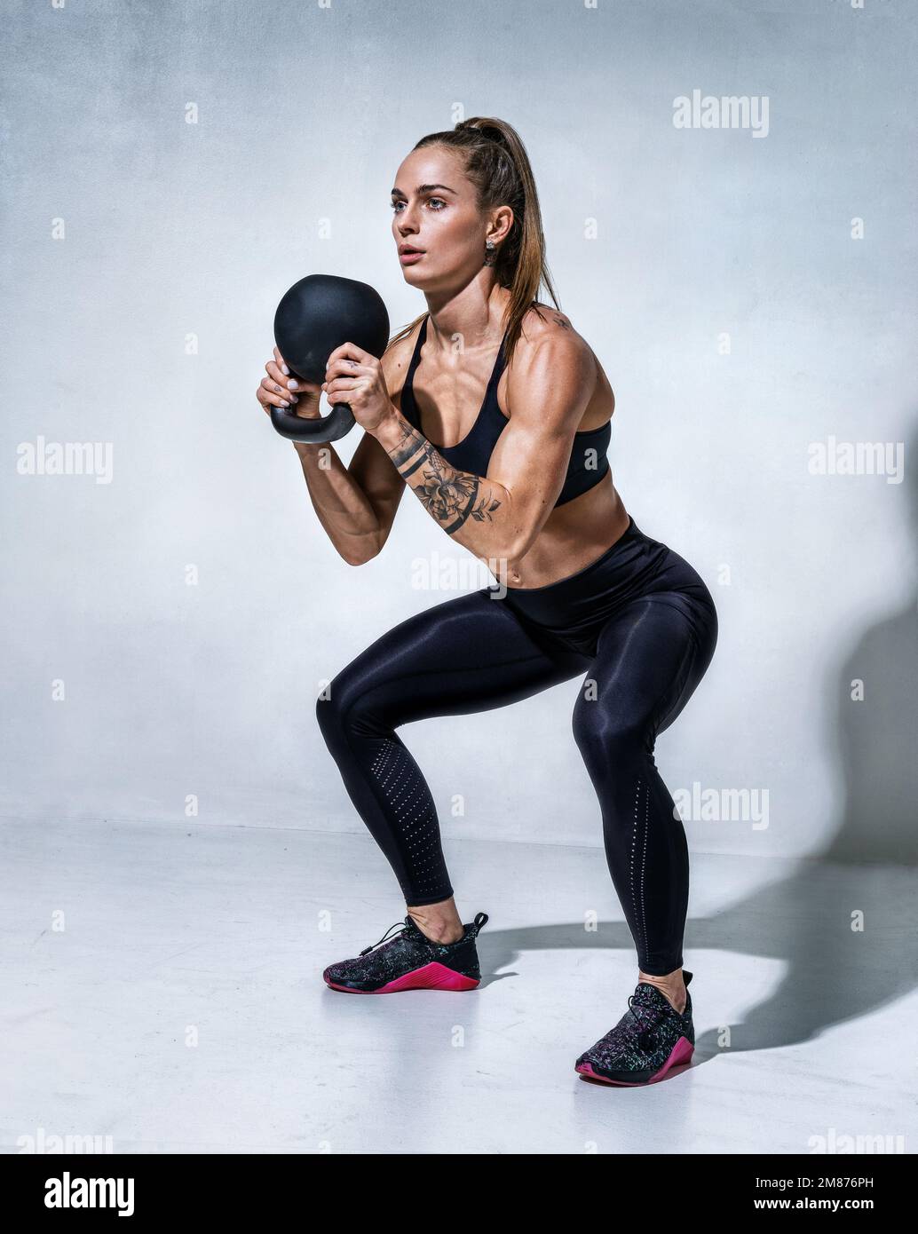 Sporty woman doing squats with kettlebell. Photo of woman with good  physique on grey background. Strength and motivation Stock Photo - Alamy