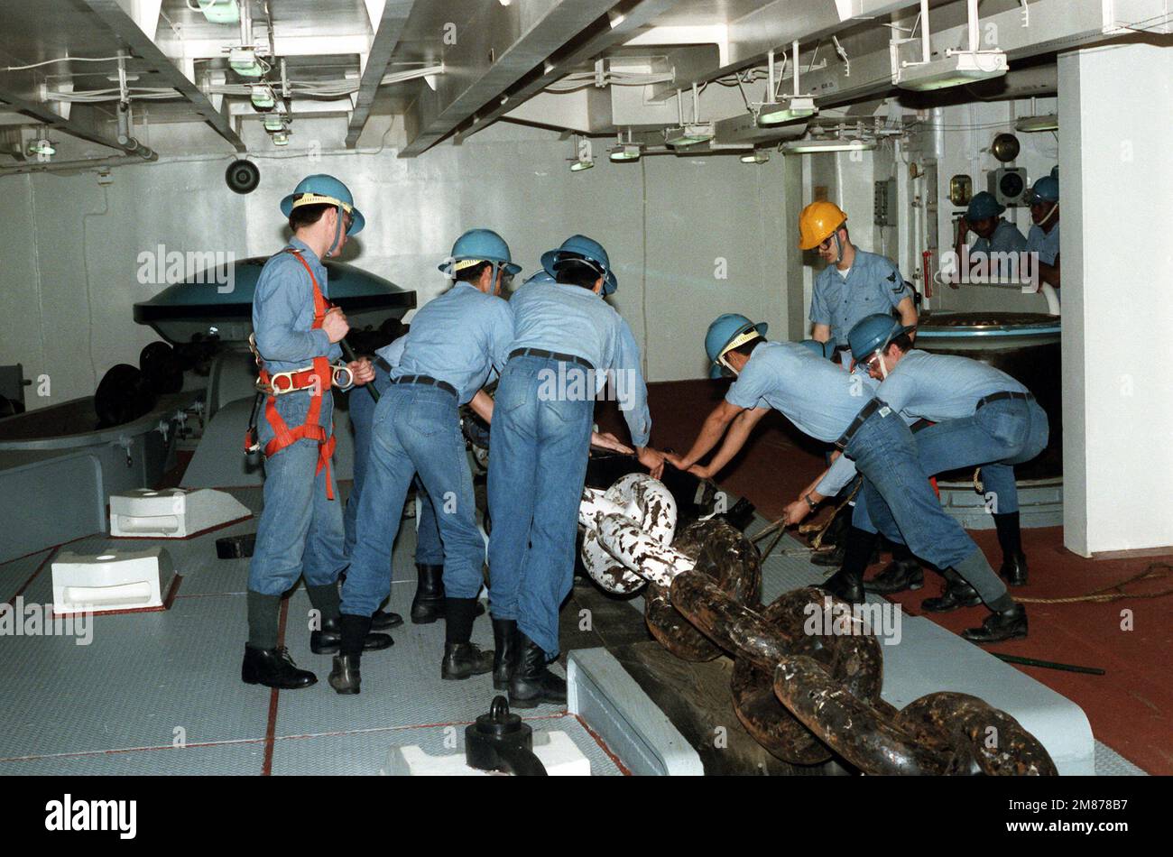Crew members lock the pelican hook to secure the anchor chain during