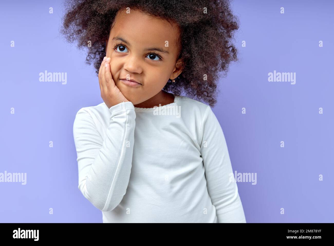young funny curious black child girl holding hands on cheeks looking