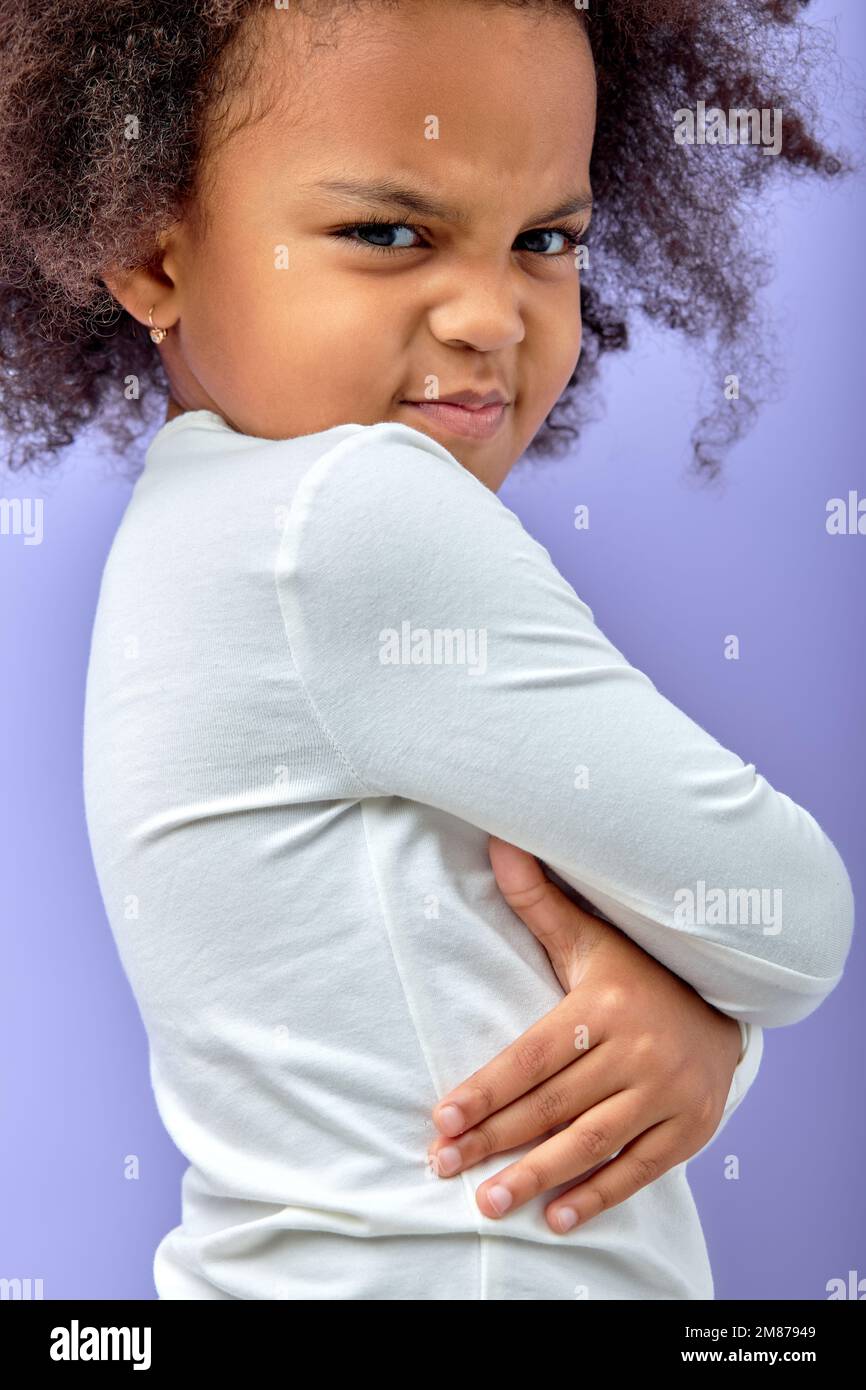 Angry little black girl showing frustration and disagreement, isolated on purple background