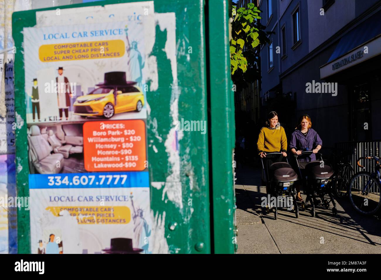 Two orthodox Jewish women push strollers on sidewalk near Lee Avenue