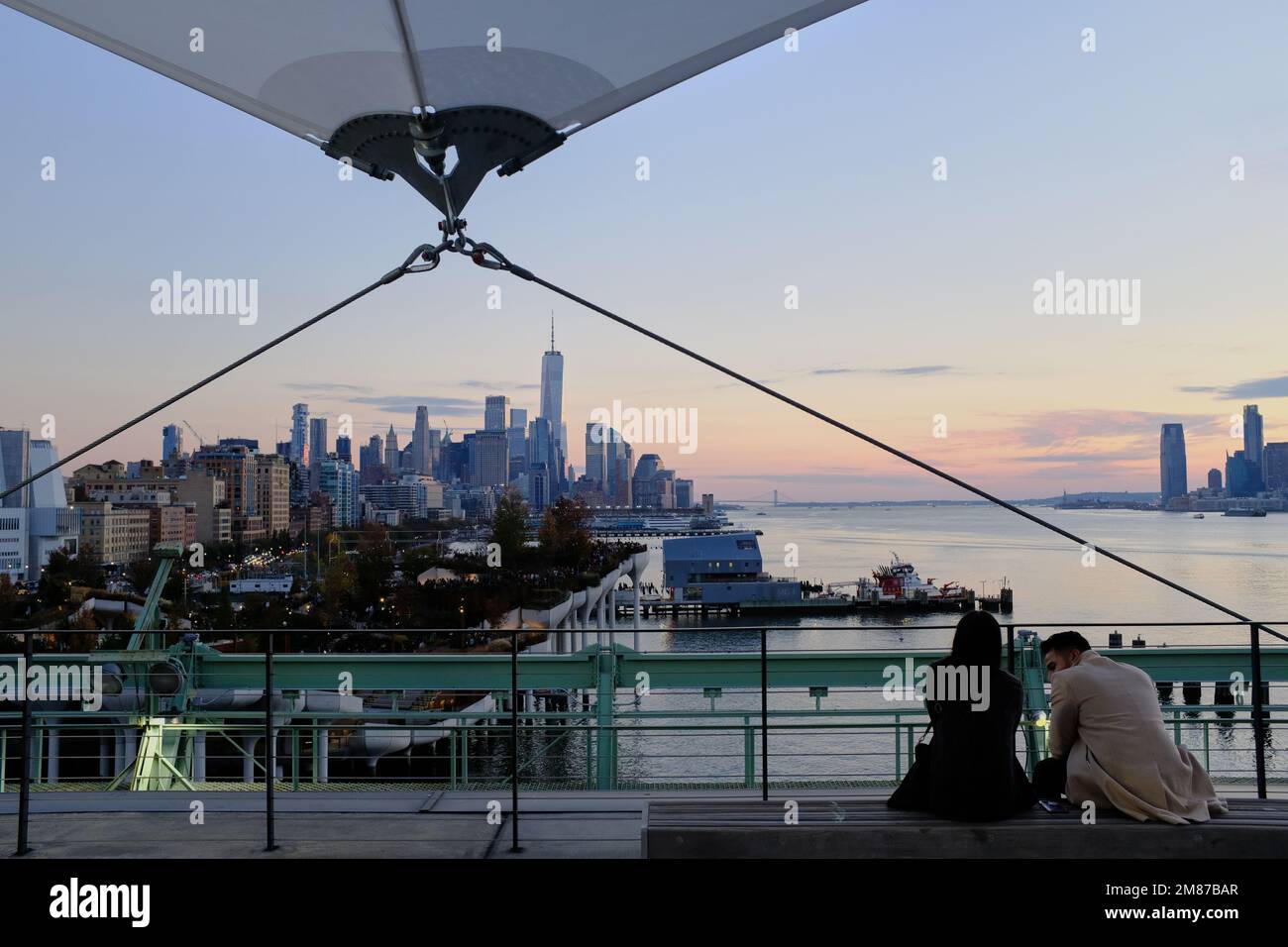 The view of Hudson River and Lower Manhattan skyline with Jersey City in distance from Pier 57 Rooftop Park with visitors.Manhattan.New York City.USA Stock Photo