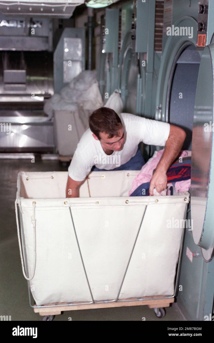 A crew member loads laundry into a clothes dryer aboard the nuclear