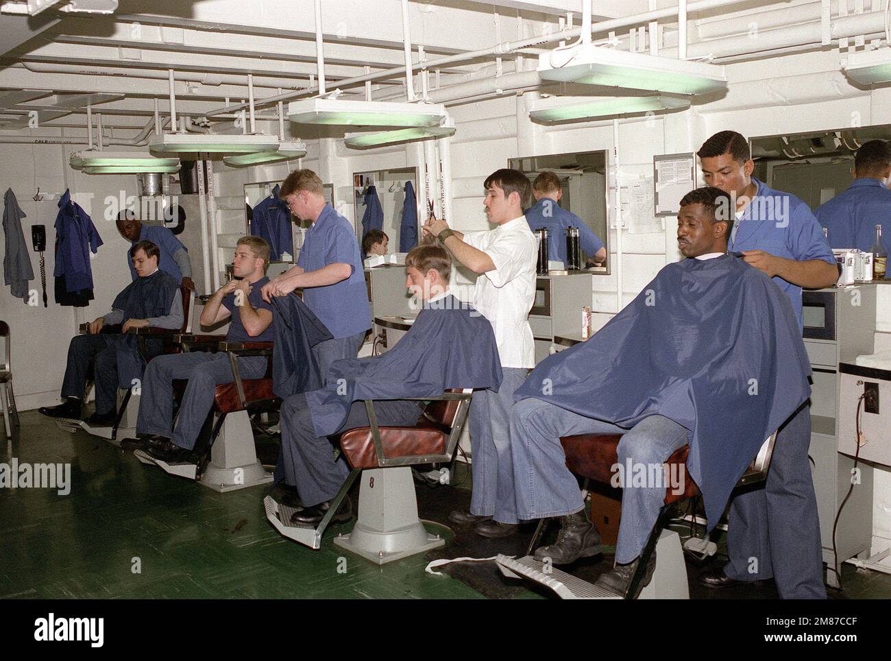 Sailors receive haircuts in the ship's barber shop aboard the nuclear