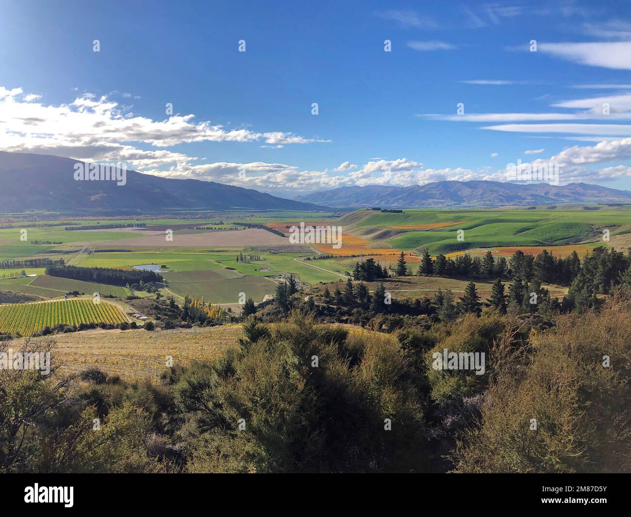 A high view from Bendigo over vineyards, green farmland and the Piza Mountain Range. Autumn blue sky and clouds. Stock Photo