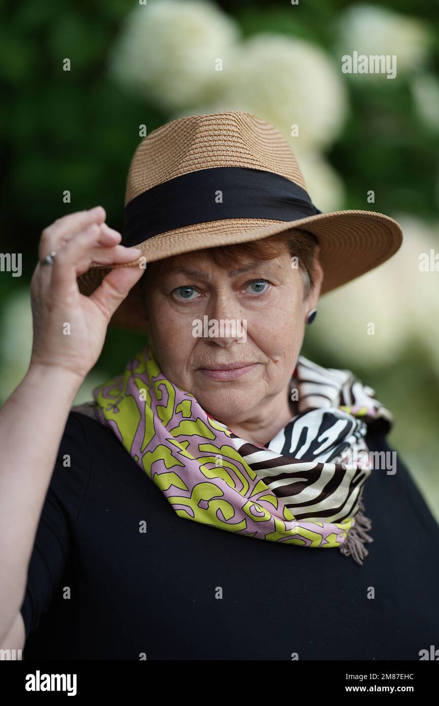 A stylish elderly woman poses in a colored neckerchief and straw hat Stock Photo