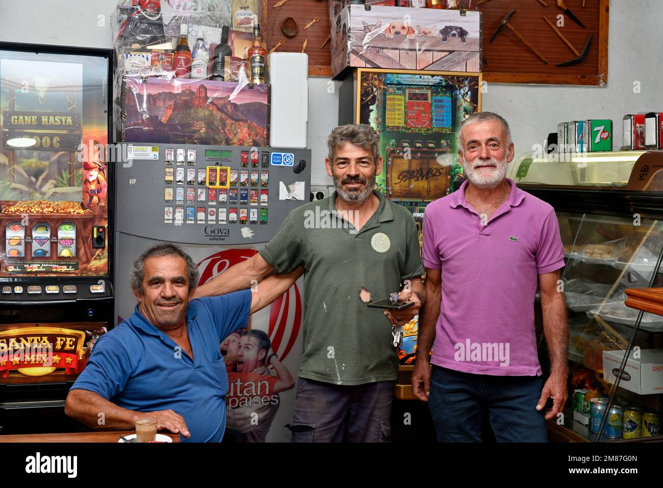 Three local men standing posing in small bar cafeteria “Los Giles” in village of Fatage, Gran Canaria Stock Photo