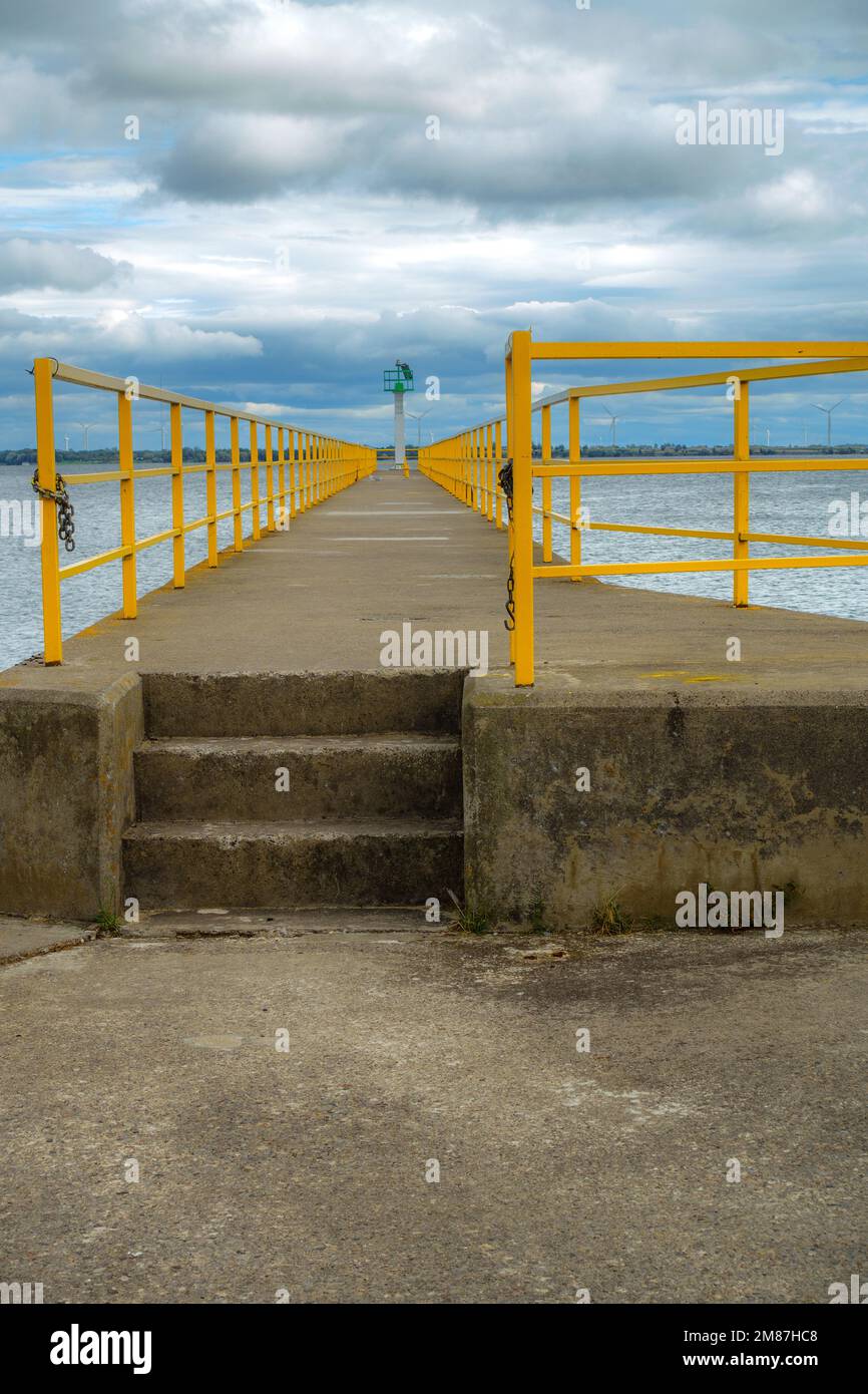 Straight pier with yellow guard rails points into the St. Lawrence River Stock Photo
