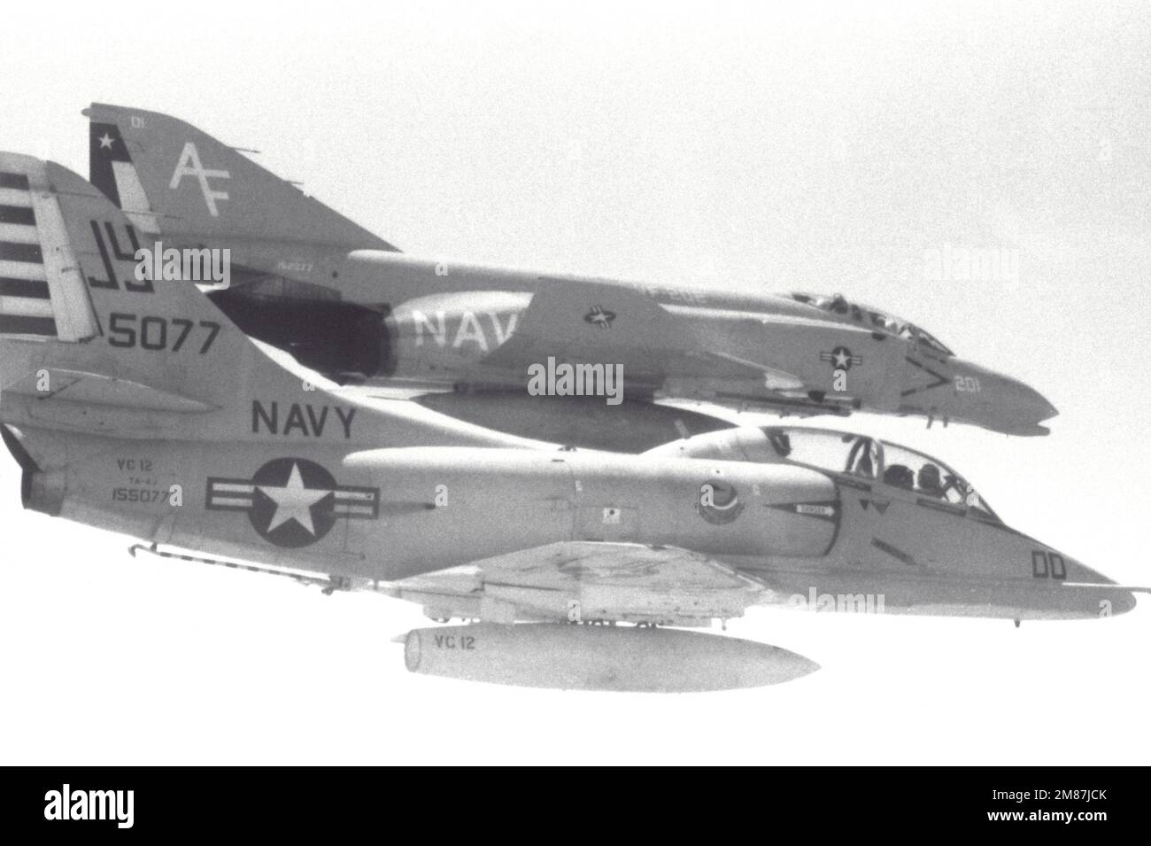 An air-to-air right side view of a Fleet Composite Squadron 12 (VC-12) TA-4J Skyhawk aircraft and a Fighter Squadron 202 (VF-202) F-4 Phantom II aircraft in formation. Country: Unknown Stock Photo
