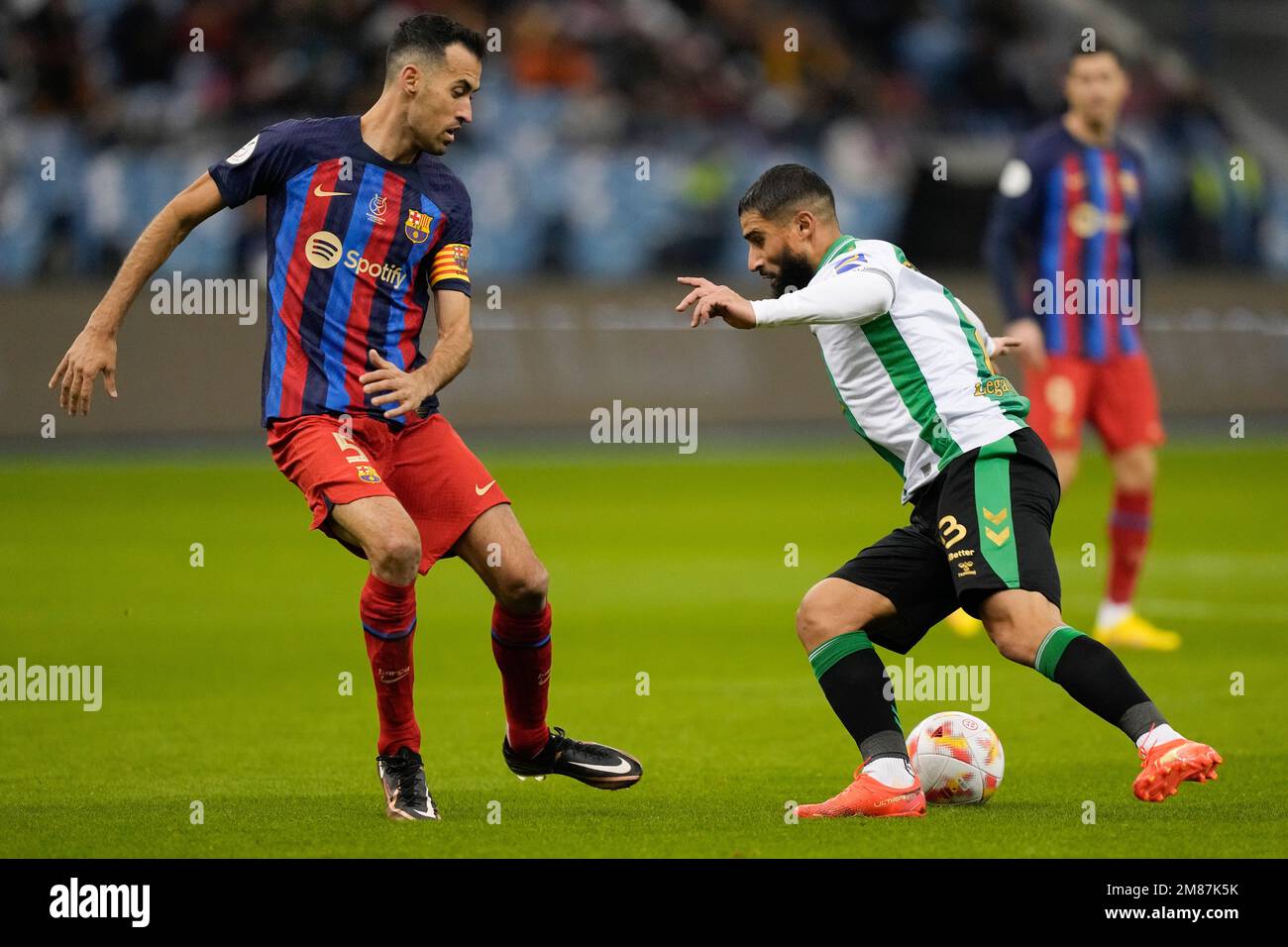 Barcelona's Sergio Busquets, left, and Betis' Nabil Fekir fight for the