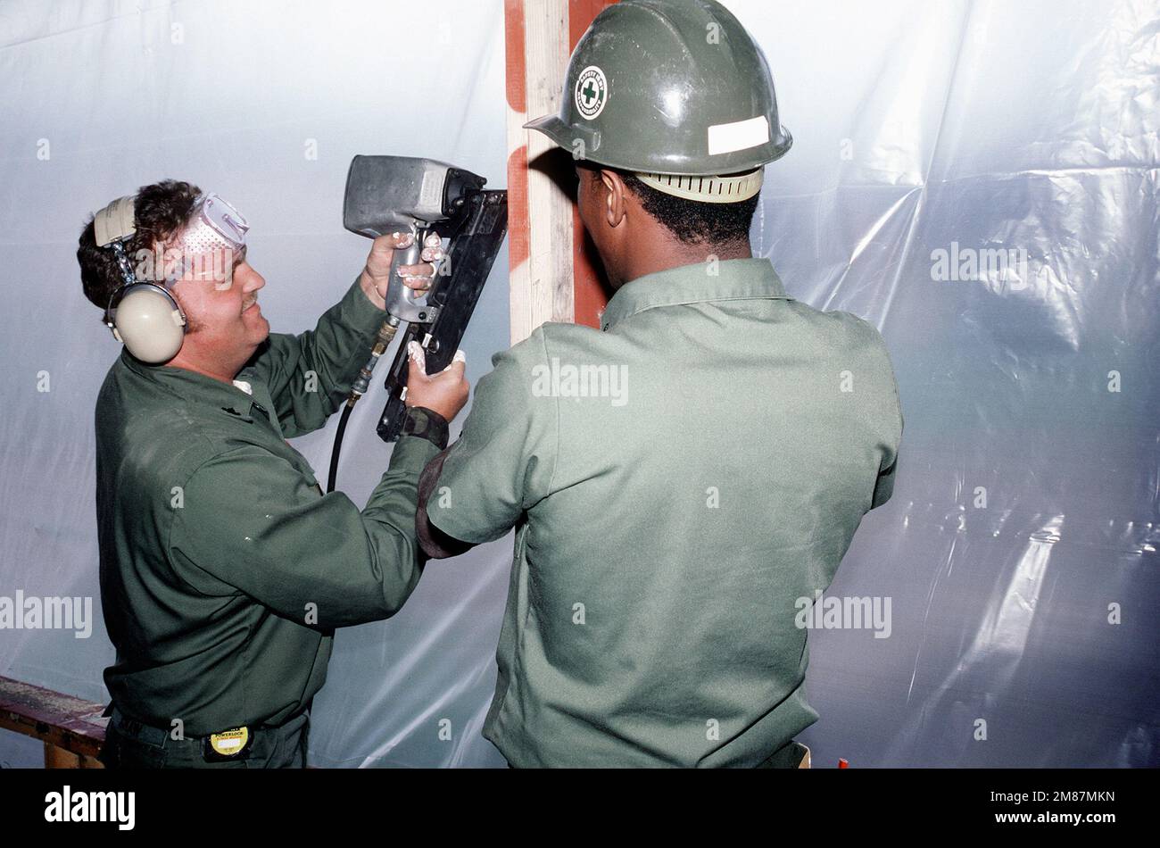 A Construction Battalion Unit 412 (CBU-412) uses a pneumatic nail