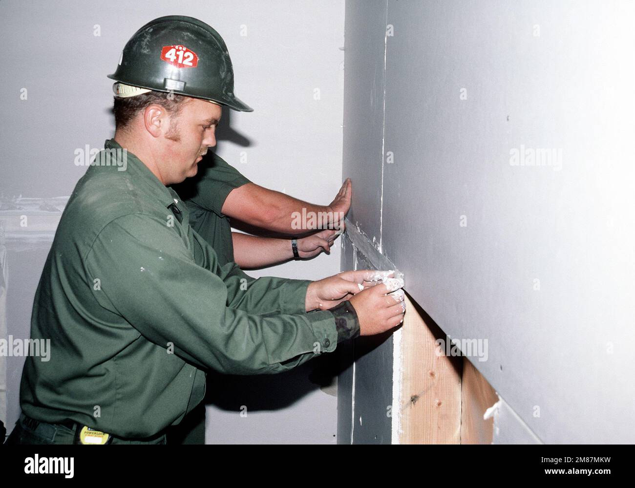 A Construction Battalion Unit 412 (CBU-412) builder applies spackling