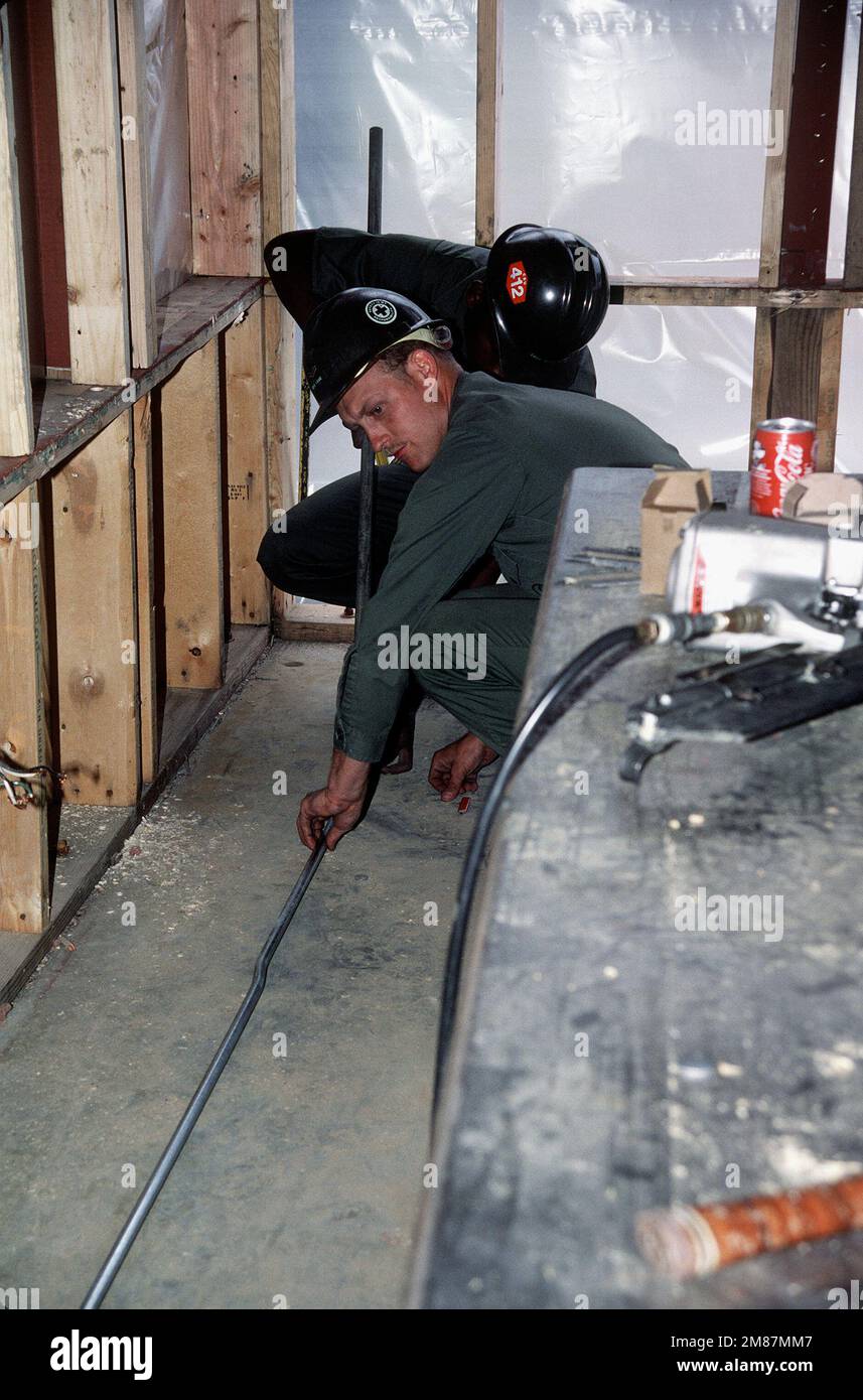 A Construction Battalion Unit 412 (CBU412) construction electrician and an apprentice prepare