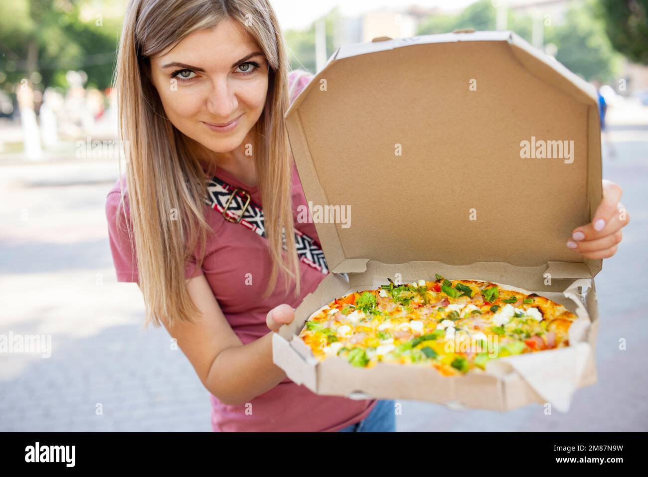 Woman holding box of takeaway pizza in her hands outdoor Stock Photo