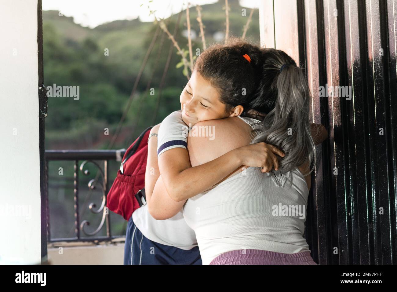 young mother saying goodbye to her little daughter before leaving for school. woman giving little girl a hug. Stock Photo