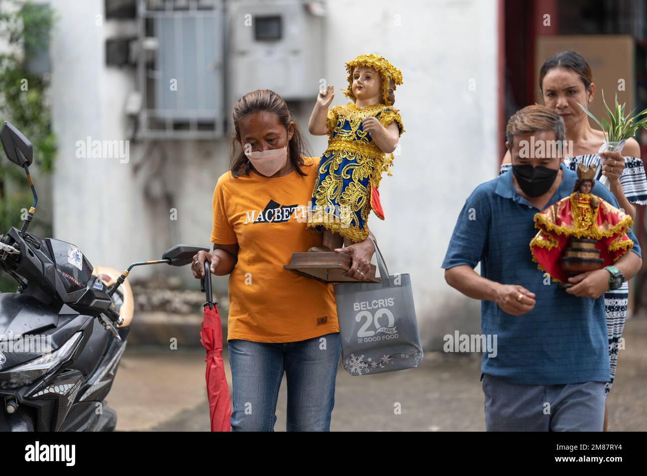 A woman carrying a large Santo Nino Figurine during the annual Sinulog Festival, Cebu City, Philippines Stock Photo