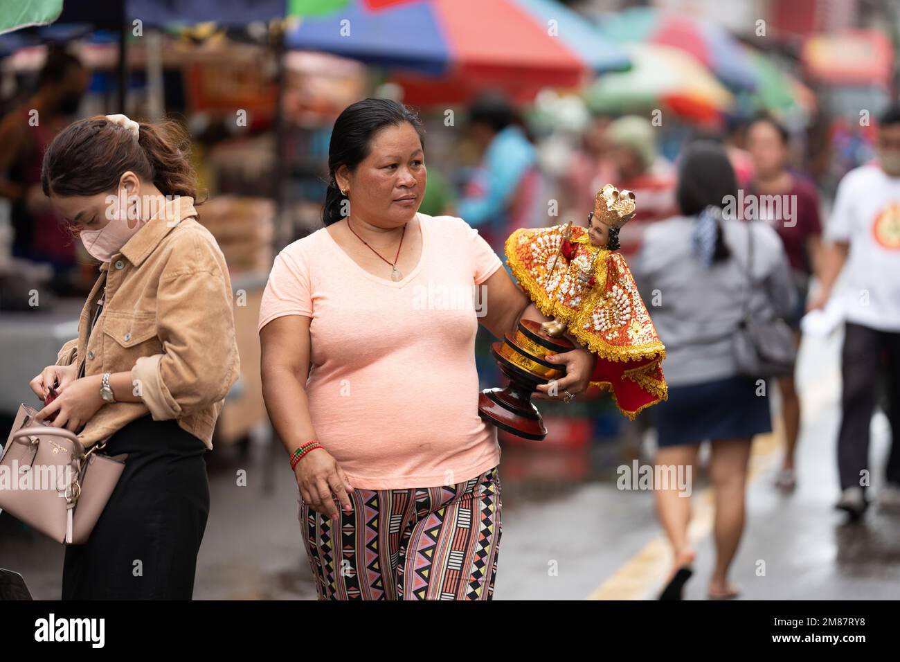 A woman carrying a large Santo Nino Figurine during the annual Sinulog Festival, Cebu City, Philippines Stock Photo