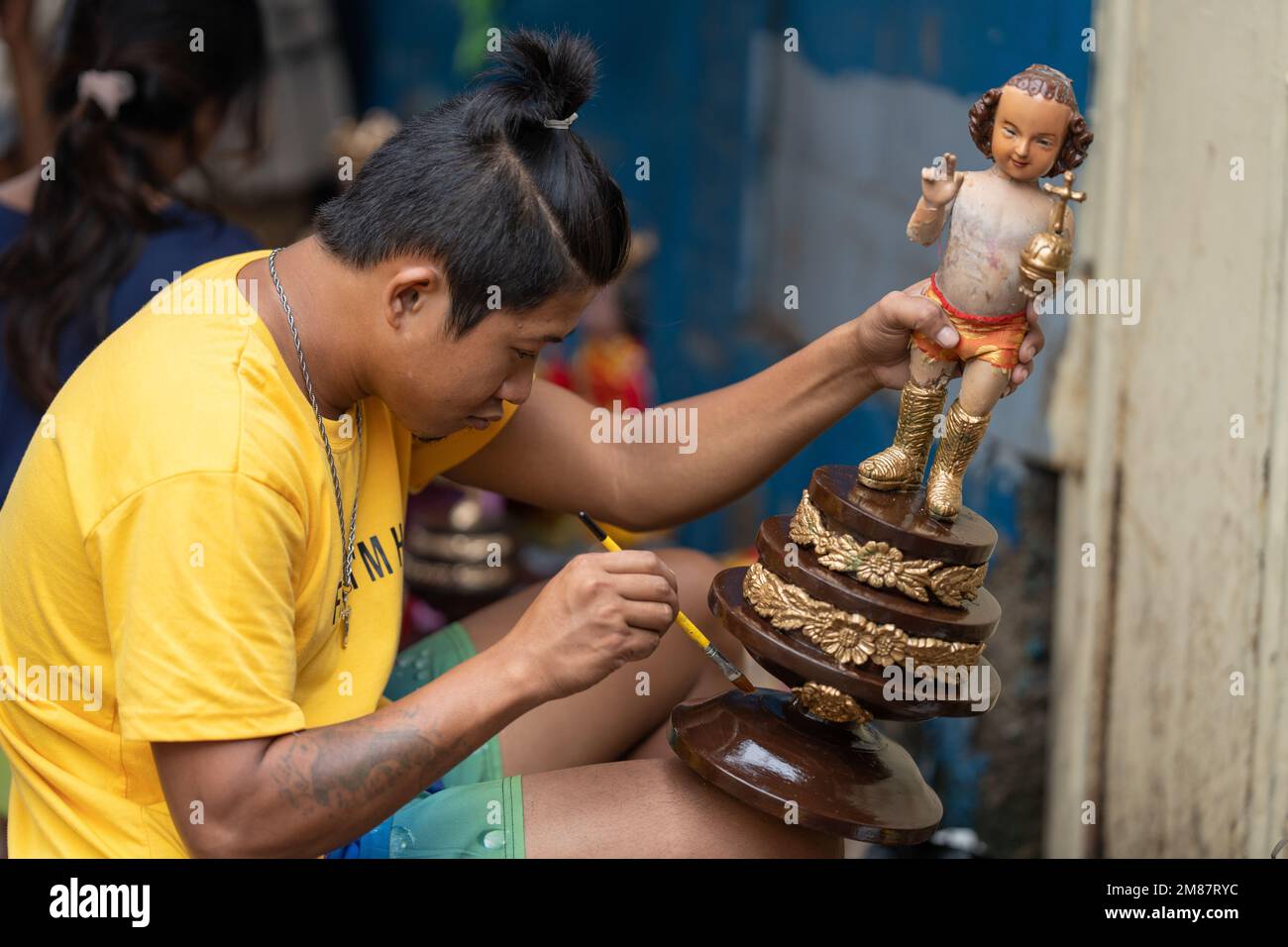 A street vendor re-decorates a Santo Nino figurine during the annual Sinulog Festival, Cebu City, Philippines Stock Photo